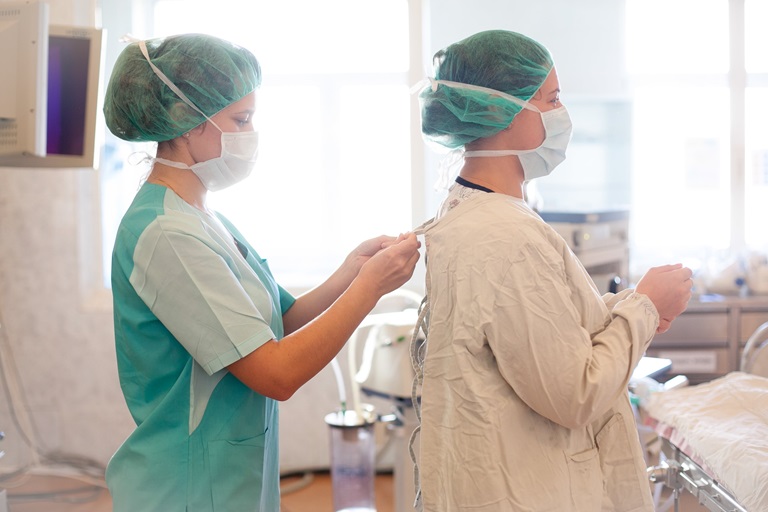 A nurse is helping another nurse to put on a sterile uniform before a surgery, hopistal no. 9, Moscow, Russia