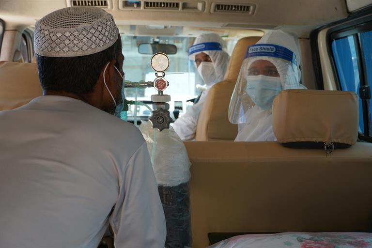 A COVID-19 patient talking with a nurse inside the ambulance on the way to UNHCR