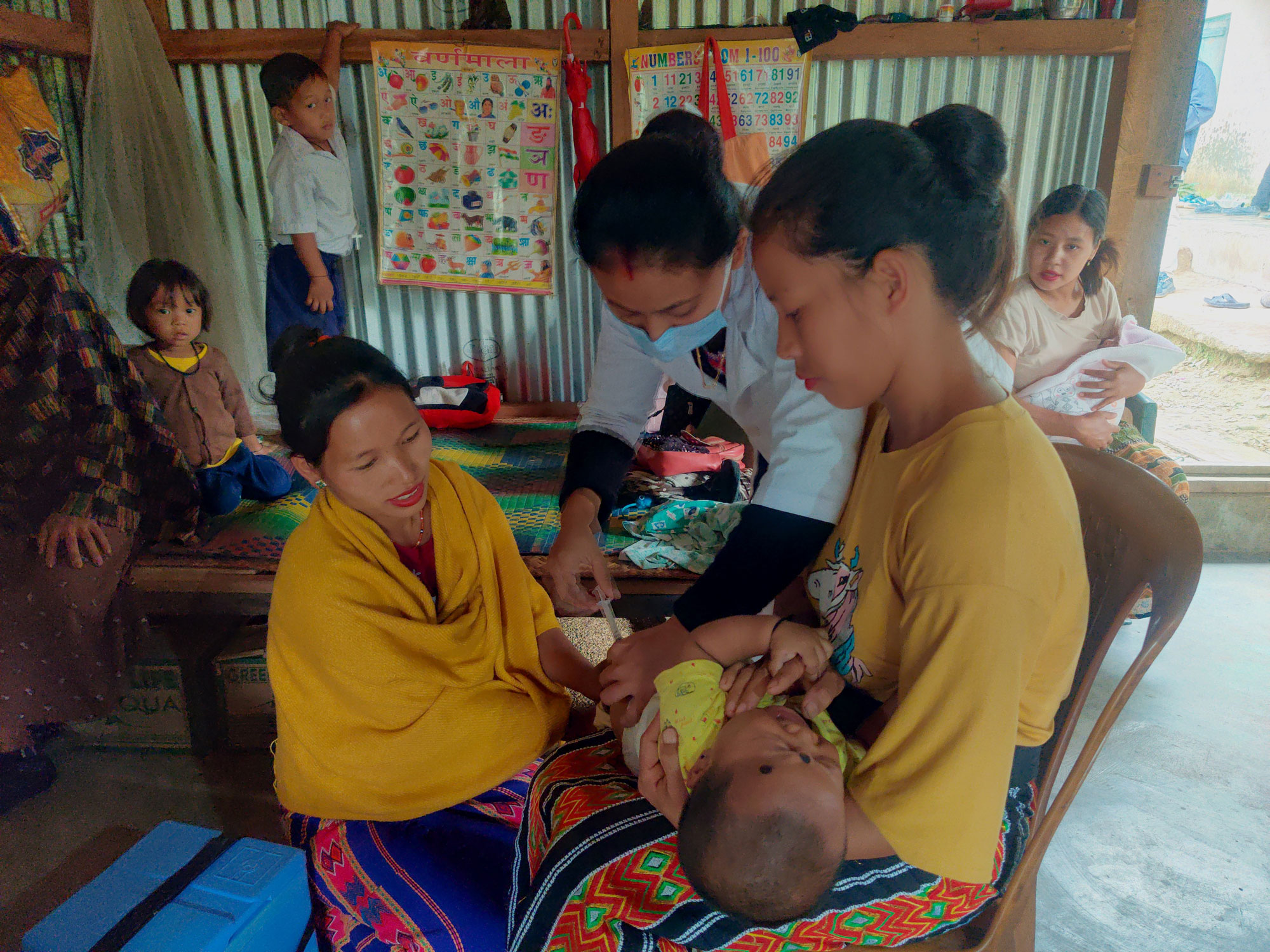 Ms Lipi Pegu, auxiliary nurse midwife from Community Health Centre Kanubari, vaccinates a baby in a makeshift immunization clinic for women and children in the hard-to-reach Chopnu village