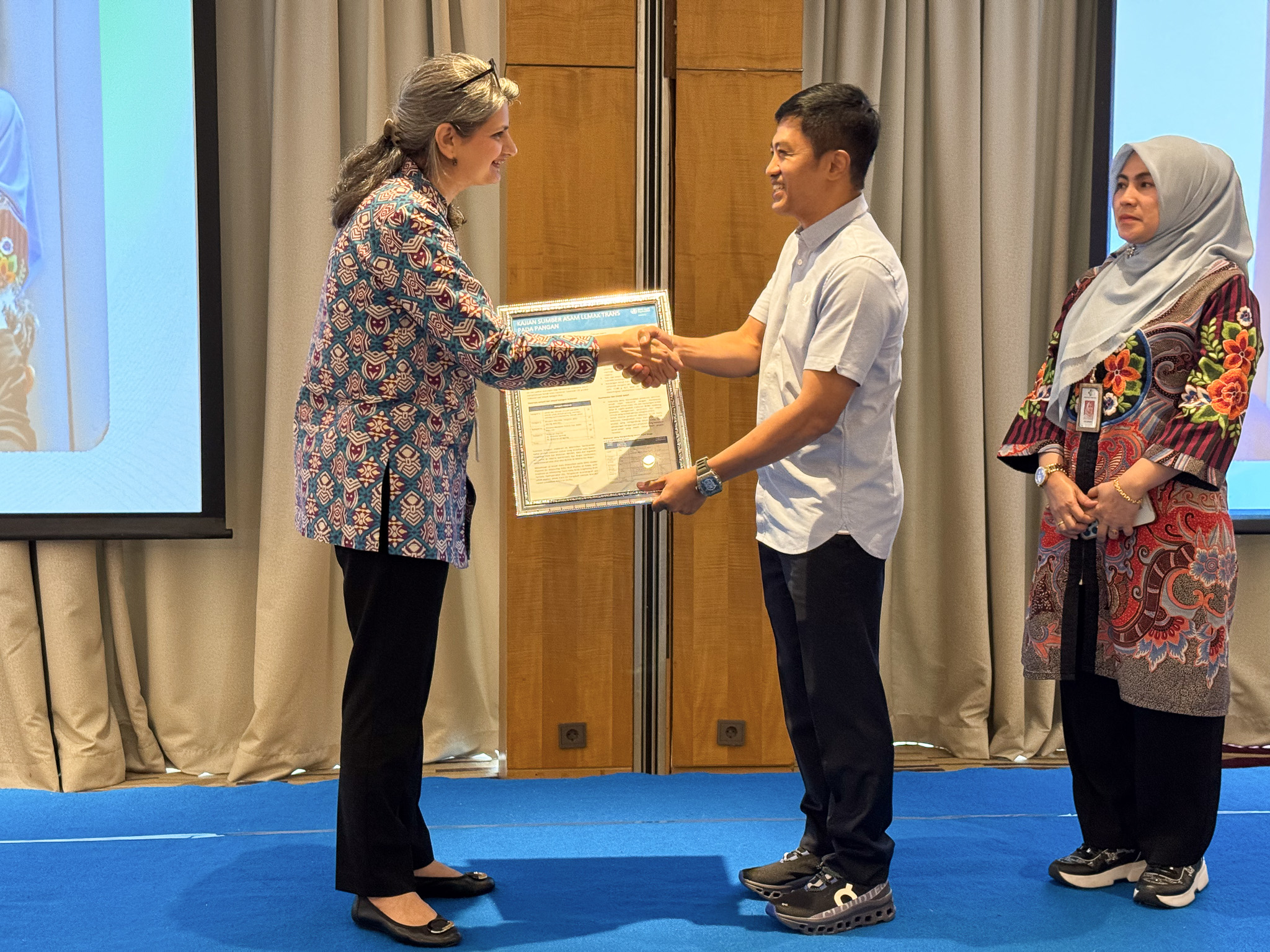 Dr. Lubna Bhatti dari WHO menyerahkan lembar fakta mengenai studi asam lemak trans kepada Prof. dr. Dante Saksono Harbuwono, Wakil Menteri Kesehatan Republik Indonesia.