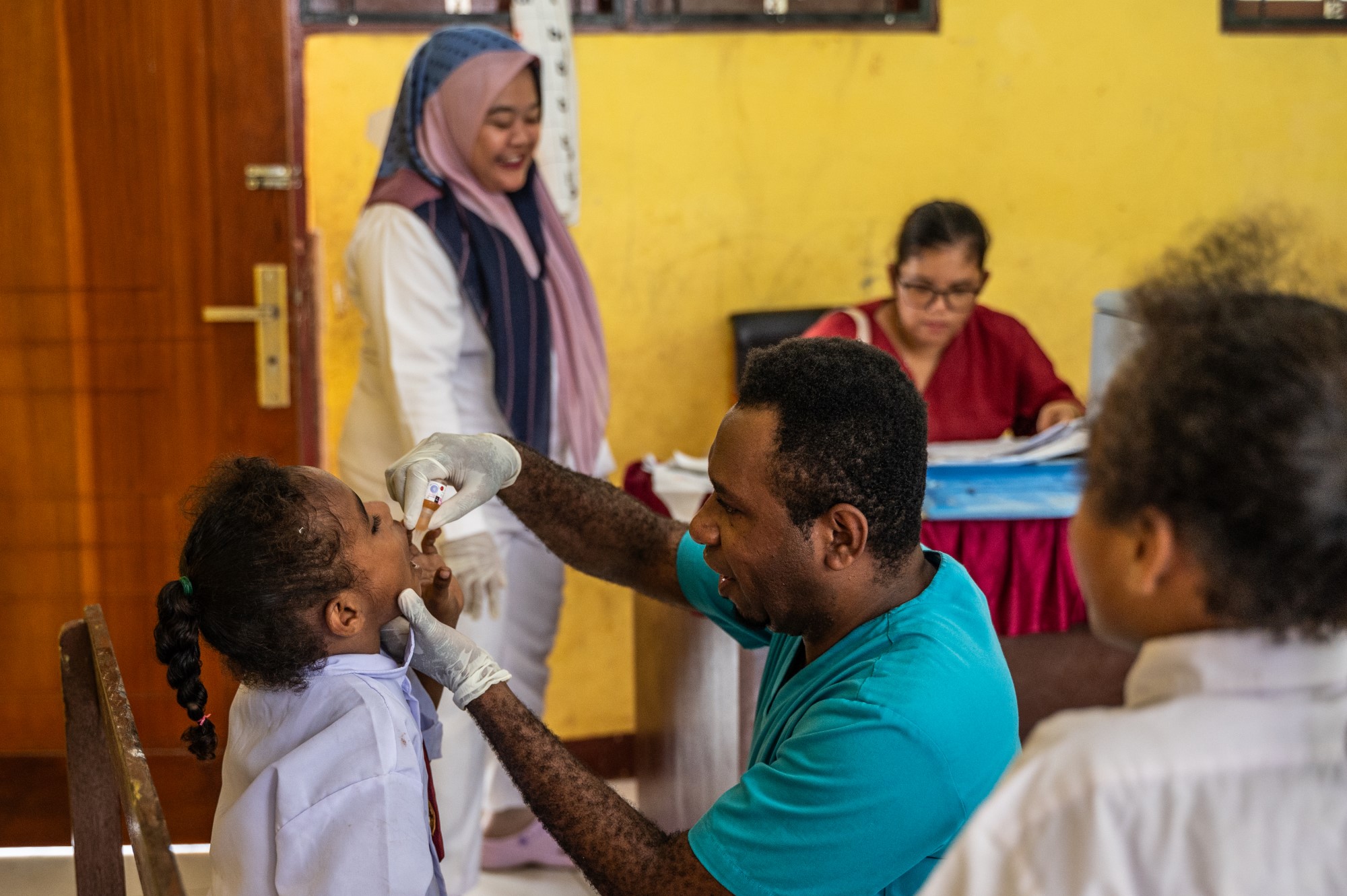 Seorang tenaga kesehatan memberikan imunisasi polio oral kepada murid SD.