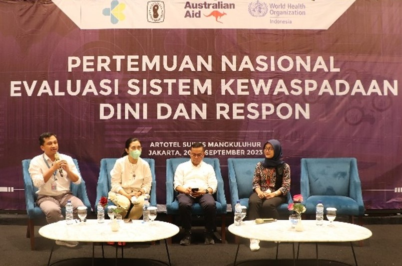 Four people as panelists, sitting on chairs on a stage.
